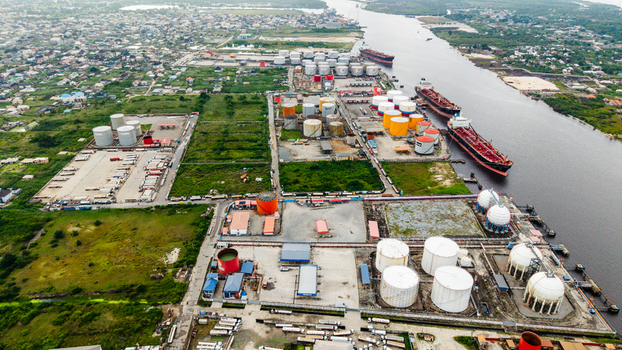 Aerial view of the industrial port and storage facility in Satellite Town with large oil tanks docked tankers and trucks in Lagos Lagos Nigeria.