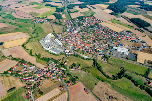 Aerial view of the town of Wachenroth featuring red roofed houses nestled among vast agricultural fields and green meadows under a clear sky in Wachenroth Bavaria Germany. Aerial view of the town of Wachenroth featuring red roofed houses nestled among vast agricultural fields and green meadows under a clear sky in Wachenroth Bavaria Germany.