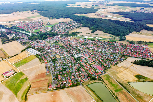 Aerial view of the town of Weisendorf featuring red roofed houses lush green forests and vast agricultural fields under a clear sky Weisendorf Bavaria Germany. Aerial view of the town of Weisendorf featuring red roofed houses lush green forests and vast agricultural fields under a clear sky Weisendorf Bavaria Germany.