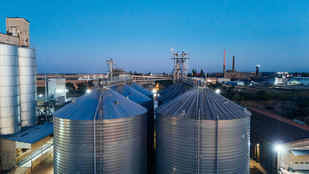Aerial view of large industrial grain silos at dusk with illuminated metal structures and storage tanks in Sremska Mitrovica Vojvodina Serbia. Aerial view of large industrial grain silos at dusk with illuminated metal structures and storage tanks in Sremska Mitrovica Vojvodina Serbia.