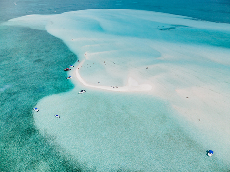 Aerial view of the Man O War Cay Sandbar with turquoise waters small boats anchored and people walking on the white sand in Rolletown Exuma The Bahamas. Aerial view of the Man O War Cay Sandbar with turquoise waters small boats anchored and people walking on the white sand in Rolletown Exuma The Bahamas.