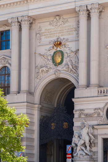 View of the ornate entrance of the Hofburg Palace featuring Corinthian columns imperial coat of arms and the statue of Hercules in Vienna Vienna Austria. View of the ornate entrance of the Hofburg Palace featuring Corinthian columns imperial coat of arms and the statue of Hercules in Vienna Vienna Austria.