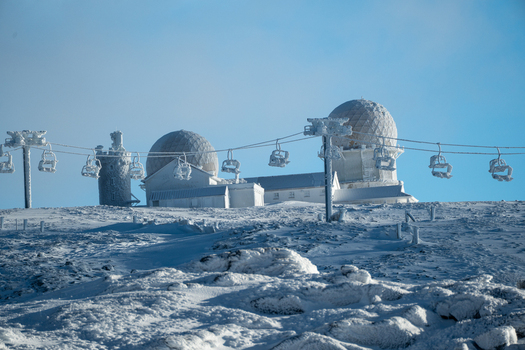 View of snow blanketed landscape with ski lifts and dome structures against a clear blue sky Torre Covilh&atilde; Distrito da Guarda Portugal.