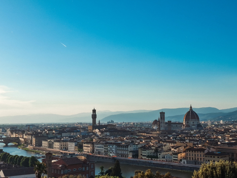 View of the historic skyline of Florence featuring the Duomo and Palazzo Vecchio along the Arno River under a clear blue sky in Florence Tuscany Italy. View of the historic skyline of Florence featuring the Duomo and Palazzo Vecchio along the Arno River under a clear blue sky in Florence Tuscany Italy.