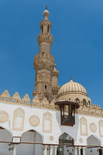 View of the intricately carved stone minaret and dome of the Al Azhar Mosque against a clear blue sky in Cairo Egypt. View of the intricately carved stone minaret and dome of the Al Azhar Mosque against a clear blue sky in Cairo Egypt.