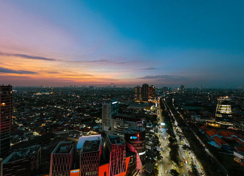 Aerial view of the sprawling cityscape of Surabaya at sunset featuring modern skyscrapers illuminated roads and a vibrant twilight sky in Surabaya East Java Indonesia. Aerial view of the sprawling cityscape of Surabaya at sunset featuring modern skyscrapers illuminated roads and a vibrant twilight sky in Surabaya East Java Indonesia.
