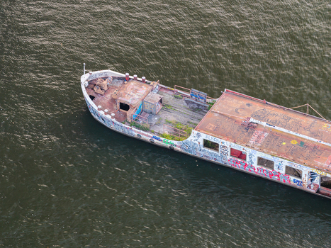 Aerial view of an abandoned graffiti covered boat floating in the water at Treptower Park in Berlin Berlin Germany. Aerial view of an abandoned graffiti covered boat floating in the water at Treptower Park in Berlin Berlin Germany.