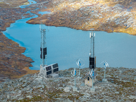Aerial view of communication towers solar panels and small wind turbines on a rocky mountain landscape next to a blue lake in Andalsnes More og Romsdal Norway.