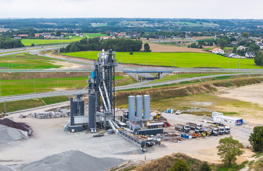 Aerial view of an asphalt mixing plant with industrial silos and machinery situated near an expressway in Pomeranian Voivodeship Poland.