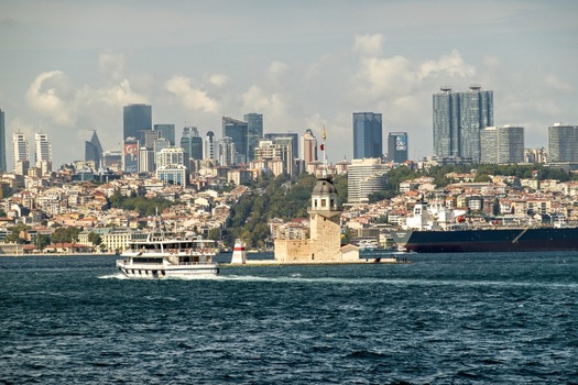 View of Maiden s Tower surrounded by the Bosphorus waters with a ferry passing by and the city skyline in the background Uskudar Istanbul Turkey. View of Maiden s Tower surrounded by the Bosphorus waters with a ferry passing by and the city skyline in the background Uskudar Istanbul Turkey.