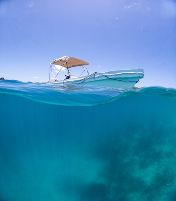 View of a small boat floating on the turquoise Caribbean sea with a clear blue sky in Guanaja Bay Islands Department Honduras. View of a small boat floating on the turquoise Caribbean sea with a clear blue sky in Guanaja Bay Islands Department Honduras.