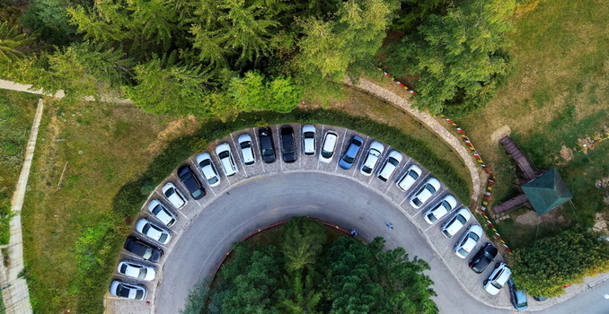 Aerial view of the curved parking lot at Brzece Sports Centar surrounded by pine trees and green grass in Brzece Rasina District Serbia.