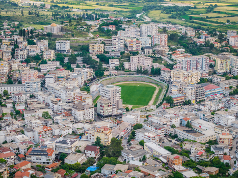 Aerial view of the urban landscape and a central football stadium surrounded by residential buildings and rolling green hills in Gjirokaster Gjirokaster County Albania. Aerial view of the urban landscape and a central football stadium surrounded by residential buildings and rolling green hills in Gjirokaster Gjirokaster County Albania.