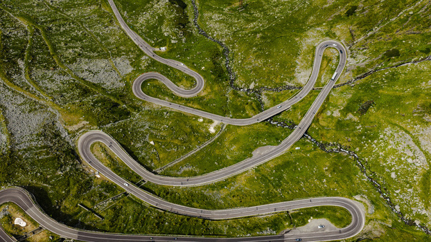 Aerial view of the winding Transfagarasan mountain road with sharp hairpin turns cutting through the lush green landscape of the Carpathian Mountains in Curtea de Arges Arges County Romania.