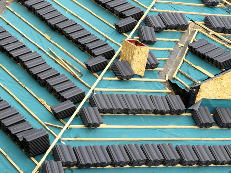 View of a roof under construction with stacks of dark grey tiles placed on wooden battens over a blue waterproof membrane in Sariyer Istanbul Turkiye.