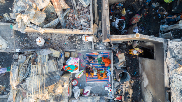 Dhaka Bangladesh 26 November 2025 Aerial view of families amidst the rubble of a fire stricken shantytown the charred remains contrasting with the bright colors of their clothes. Dhaka Bangladesh 26 November 2025 Aerial view of families amidst the rubble of a fire stricken shantytown the charred remains contrasting with the bright colors of their clothes.