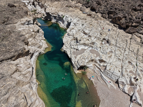 Aerial view of the tranquil turquoise waters winding through the stark rocky landscape of Kalysan Canyon a hidden oasis of natural beauty Kalysan Socotra Yemen. Aerial view of the tranquil turquoise waters winding through the stark rocky landscape of Kalysan Canyon a hidden oasis of natural beauty Kalysan Socotra Yemen.
