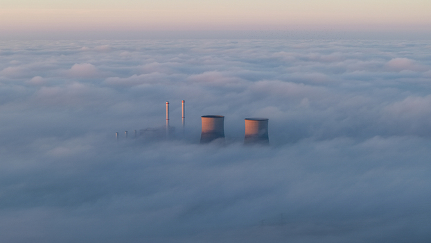 Aerial view of RWE Clauscentrale power plant with cooling towers and chimneys rising above a dense layer of fog under a soft morning sky Maasbracht Limburg Netherlands. Aerial view of RWE Clauscentrale power plant with cooling towers and chimneys rising above a dense layer of fog under a soft morning sky Maasbracht Limburg Netherlands.