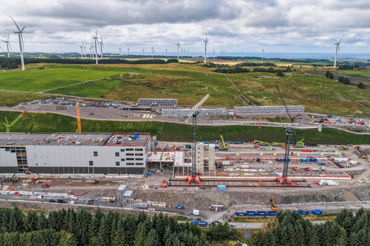 Aerial view of the Green Mountain SVG Undheim Datasenter construction site with industrial buildings cranes and wind turbines in the green landscape of Undheim Rogaland Norway. Aerial view of the Green Mountain SVG Undheim Datasenter construction site with industrial buildings cranes and wind turbines in the green landscape of Undheim Rogaland Norway.