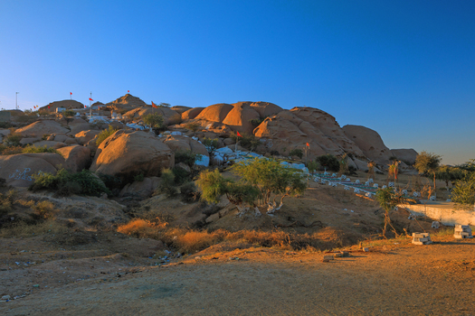 View of Chorio temple situated on a rocky hill with red flags fluttering in the golden sunset light in the arid landscape of Nagarparkar Sindh Pakistan.