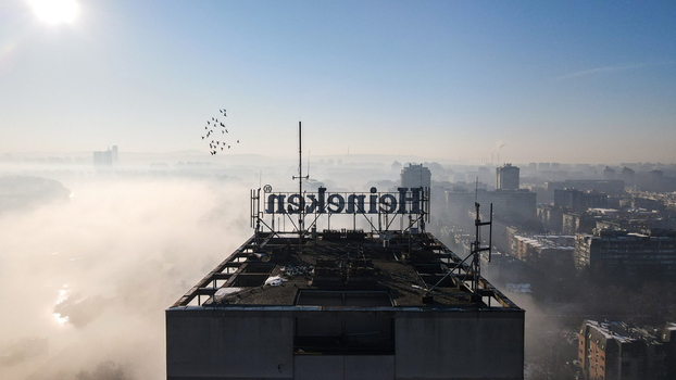 Belgrade Serbia 16 January 2022 Aerial view of the Heineken sign on a rooftop overlooking the foggy cityscape of Belgrade with birds flying in the morning light. Belgrade Serbia 16 January 2022 Aerial view of the Heineken sign on a rooftop overlooking the foggy cityscape of Belgrade with birds flying in the morning light.