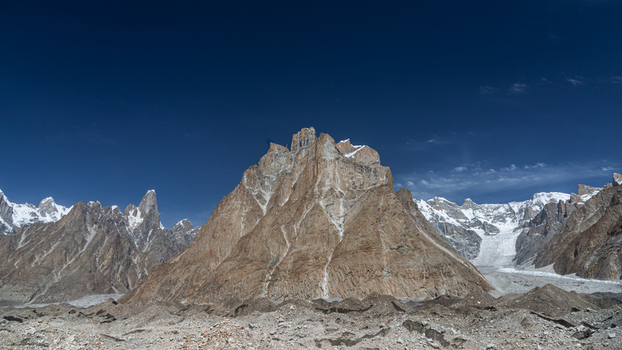 View of the majestic Baltoro Glacier surrounded by rugged mountain peaks and rocky terrain under a clear blue sky in Baltoro Gilgit Baltistan Pakistan.