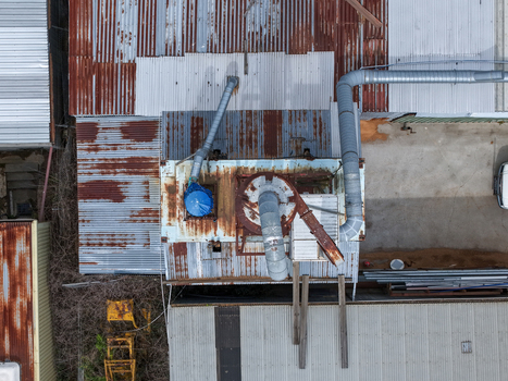 Melbourne VIC Australia 25 September 2026 Aerial view of industrial factory site with rusted corrugated metal roofs ventilation pipes and machinery.