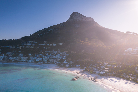 Aerial view of Lion s Head mountain peak overlooking the white sands and turquoise waters of Camps Bay beach during golden hour in Cape Town Western Cape South Africa. Aerial view of Lion s Head mountain peak overlooking the white sands and turquoise waters of Camps Bay beach during golden hour in Cape Town Western Cape South Africa.