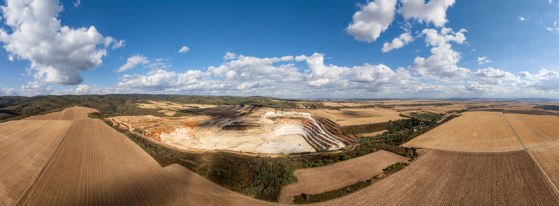 Aerial view of the Besenovo quarry showing the large open pit excavation site surrounded by vast agricultural fields under a bright blue sky in Besenovo Vojvodina Serbia.