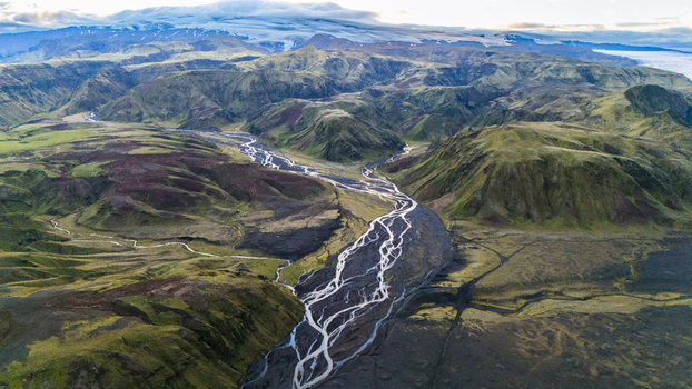 Aerial view of the braided river flowing through the dramatic green mountains and volcanic landscape of Thakgil near Vik Myrdalshreppur Iceland.
