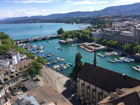 View of the Limmat river flowing into Lake Zurich with boats docked at the marina historic buildings and the Fraumunster church in Zurich Zurich Switzerland.
