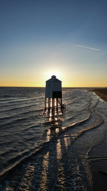 Aerial view of Burnham on Sea Low Lighthouse standing in the sea with golden light reflecting on the water and waves along the sandy beach in Burnham on Sea England United Kingdom. Aerial view of Burnham on Sea Low Lighthouse standing in the sea with golden light reflecting on the water and waves along the sandy beach in Burnham on Sea England United Kingdom.
