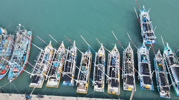Aerial view of multiple traditional fishing boats docked in the harbor with clear turquoise water in Bakauheni Lampung Indonesia.