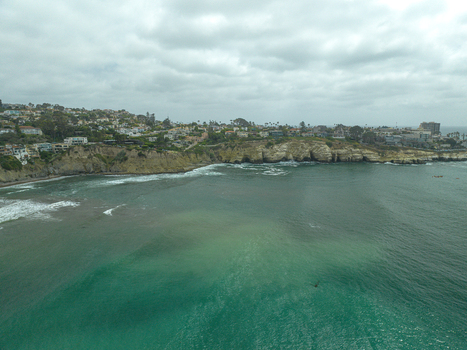Aerial view of La Jolla Cove with rugged cliffs coastal houses and turquoise ocean water under a cloudy sky in San Diego California United States. Aerial view of La Jolla Cove with rugged cliffs coastal houses and turquoise ocean water under a cloudy sky in San Diego California United States.