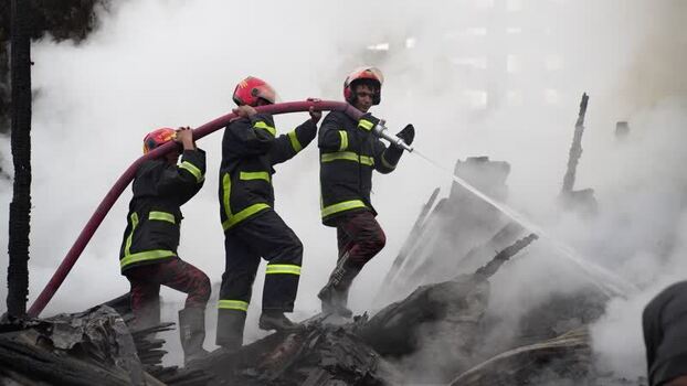 View of firefighters battling a blaze with a water hose Bangladesh. View of firefighters battling a blaze with a water hose Bangladesh.