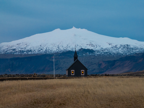 Aerial view of the iconic black church of Budir with glowing windows set against the snow capped Snaefellsjokull glacier in a vast grassy landscape in Budir Snaefellsbaer Iceland. Aerial view of the iconic black church of Budir with glowing windows set against the snow capped Snaefellsjokull glacier in a vast grassy landscape in Budir Snaefellsbaer Iceland.