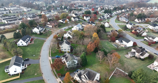 Aerial view of a suburban neighborhood with detached houses winding roads and autumn trees in Millersville Pennsylvania United States.