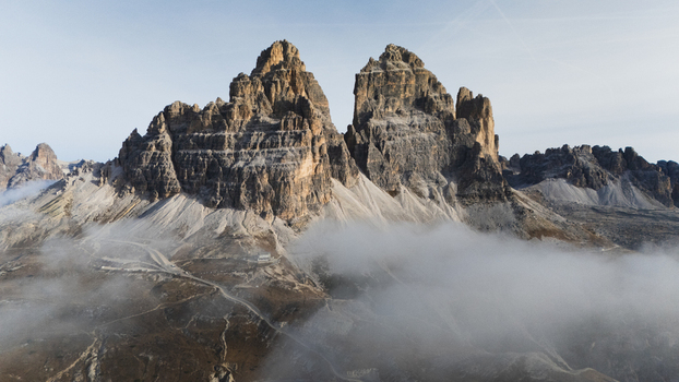 Aerial view of Tre Cime di Lavaredo peaks rising above a thick layer of white clouds under a clear sky Auronzo di Cadore Italy Aerial view of Tre Cime di Lavaredo peaks rising above a thick layer of white clouds under a clear sky Auronzo di Cadore Italy
