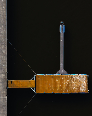 Aerial view of a floating wooden dock on dark water with a narrow walkway extending from a concrete pier in Plock Masovian Voivodeship Poland.