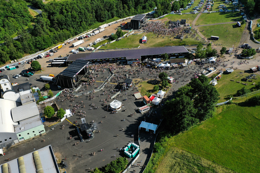 Geiselwind Germany 21 June 2025 Aerial view of Eventzentrum Strohofer Geiselwind musichall with outdoor stages crowds of people and festival tents under a clear sky. Geiselwind Germany 21 June 2025 Aerial view of Eventzentrum Strohofer Geiselwind musichall with outdoor stages crowds of people and festival tents under a clear sky.