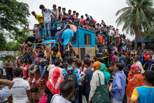 Dhaka Bangladesh 15 June 2018 View of a crowded train at Airport Railway Station with people sitting on the roof and hanging from the sides during the festival rush. Dhaka Bangladesh 15 June 2018 View of a crowded train at Airport Railway Station with people sitting on the roof and hanging from the sides during the festival rush.