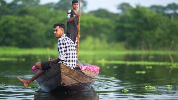 View of two men in a wooden boat with pink water lilies Bangladesh. View of two men in a wooden boat with pink water lilies Bangladesh.
