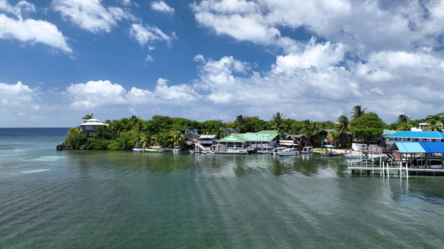 Aerial view of the coastal village of West End with wooden docks boats moored in turquoise water and lush tropical vegetation in West End Bay Islands Department Honduras.