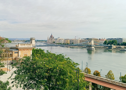 View of the Szechenyi Chain Bridge spanning the Danube River with the Hungarian Parliament Building in the background under a soft sky in Budapest Hungary. View of the Szechenyi Chain Bridge spanning the Danube River with the Hungarian Parliament Building in the background under a soft sky in Budapest Hungary.