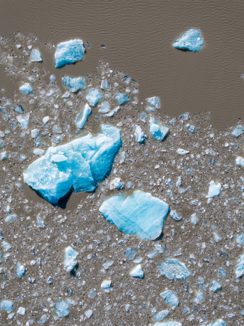 Aerial view of bright blue icebergs floating in dark silty glacial water in Iceland. Aerial view of bright blue icebergs floating in dark silty glacial water in Iceland.