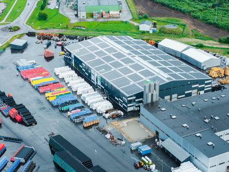 Jelgava Latvia 04 July 2026 Aerial view of the Evopipes industrial facility featuring large warehouse buildings and extensive outdoor storage of colorful polymer pipe systems.