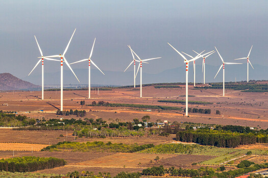 Aerial view of the Phuoc Dinh Wind Farm with large wind turbines standing in a vast arid landscape with patches of green vegetation in Phuoc Dinh Ninh Thuan Vietnam. Aerial view of the Phuoc Dinh Wind Farm with large wind turbines standing in a vast arid landscape with patches of green vegetation in Phuoc Dinh Ninh Thuan Vietnam.