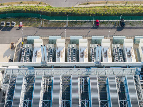 Aerial view of the Vantage Data Centers BER1 facility featuring rows of industrial cooling units and HVAC systems on the rooftop with a parking area in Ludwigsfelde Brandenburg Germany. Aerial view of the Vantage Data Centers BER1 facility featuring rows of industrial cooling units and HVAC systems on the rooftop with a parking area in Ludwigsfelde Brandenburg Germany.
