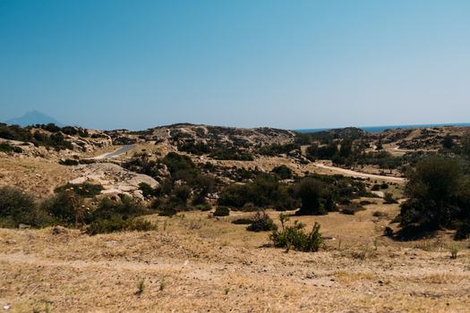 View of the arid landscape with rocky hills sparse vegetation and a winding road near the coast in Neos Marmaras Greece.