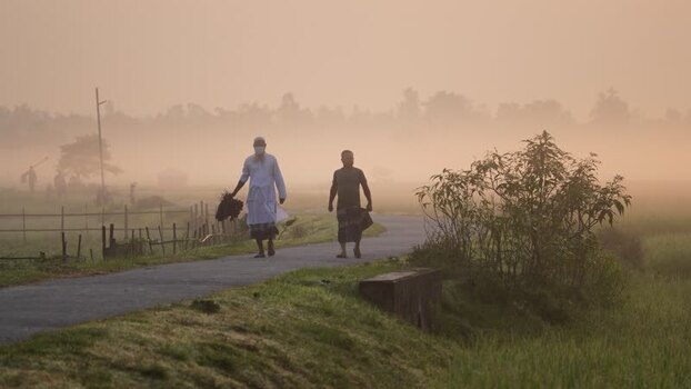 View of men walking on a misty rural road in Bogura Bangladesh.
